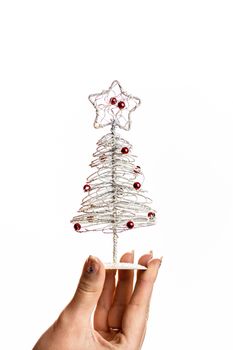 Hand holding small silver wire Christmas tree isolated on white background