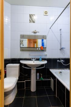 General view of a classic bathroom interior in an apartment, with black and white tiles