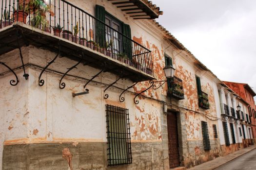 Old white facades, balconies and vintage lanterns in a street of Villanueva de los Infantes, Ciudad Real, Spain