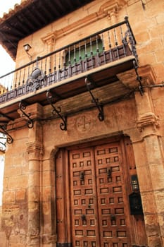 Old stone facade made of carved stone and vintage wooden door in a majestic house in Villanueva de los Infantes, Ciudad Real community, Spain