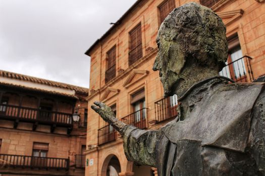 Villanueva de los Infantes square and Don Quixote statue in the foreground in spring under cloudy sky