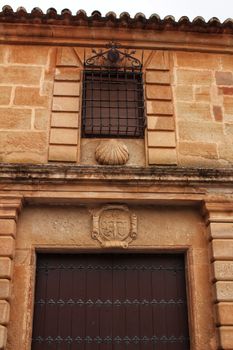 Old stone facade made of carved stone and vintage wooden door in a majestic house in Villanueva de los Infantes, Ciudad Real community, Spain