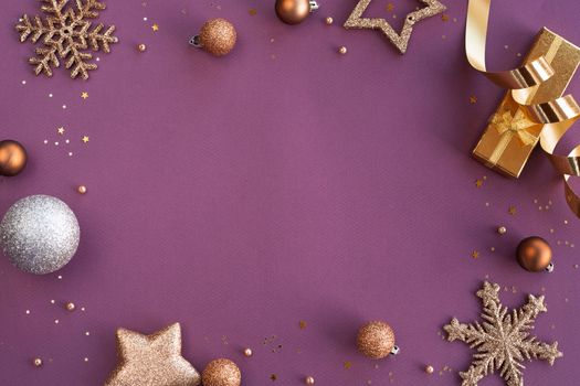 Christmas Border frame of golden glitter ornaments on purple paper background with copy space for text