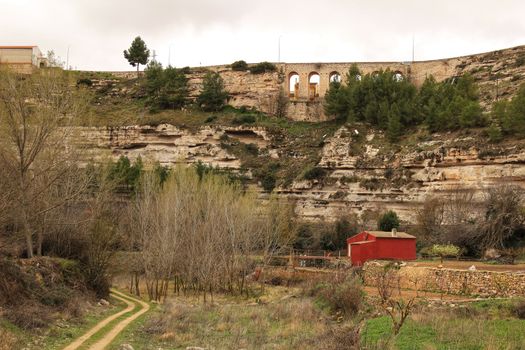 Mountain landscape with wooden house and view of old stone aqueduct in Jorquera, Spain