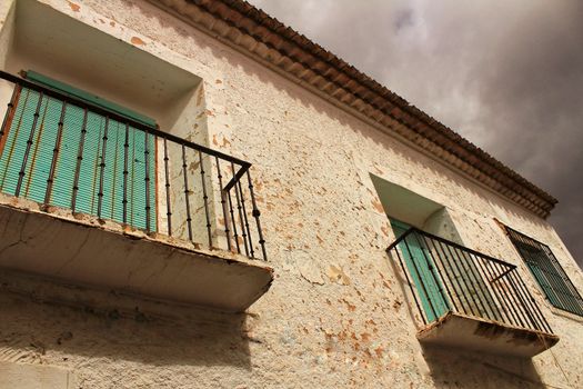 Old house facade with rusty balcony and green blind. Alcaraz village, Castilla La Mancha, Spain.