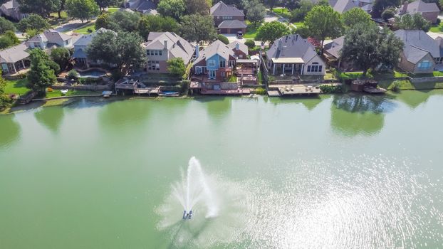 Top view upscale lakeside houses with water fountain in Flower Mound, Texas, America. Row of two story waterfront homes with private docking, swimming pools. Wealthy residential area