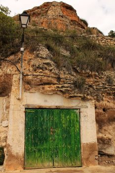 Old garage with green wooden door excavated in the mountain in Alcaraz