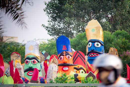 colorful ravana effigies placed on a busy street with traffic passing by to be purchased and filled with fireworks for the hindu festival of dussehra or vijay dashmi celebrating the victory of good over evil as given in the indian epic of ramayana