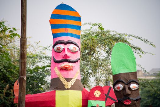 colorful ravana effigies placed on a busy street with traffic passing by to be purchased and filled with fireworks for the hindu festival of dussehra or vijay dashmi celebrating the victory of good over evil as given in the indian epic of ramayana