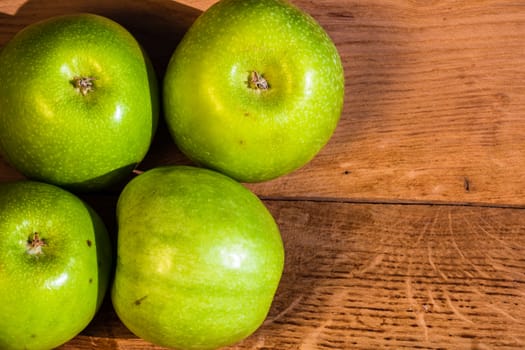 Detail on ripe green apples on wooden table.