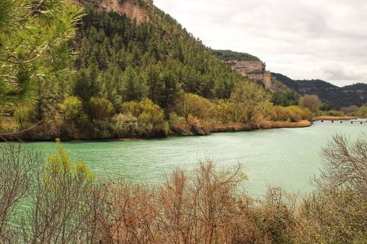 Tolosa reservoir surrounded by vegetation and mountains in Alcala del Jucar village, Albacete, Spain