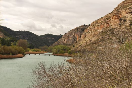 Tolosa reservoir surrounded by vegetation and mountains in Alcala del Jucar village, Albacete, Spain