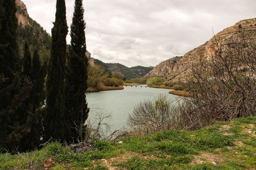 Tolosa reservoir surrounded by vegetation and mountains in Alcala del Jucar village, Albacete, Spain