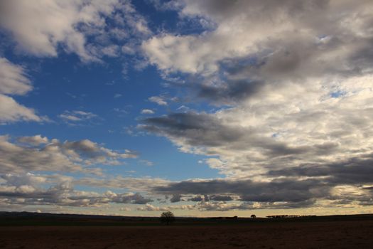 Landscape with cloudy sky and farm field in Castilla La Mancha, Spain