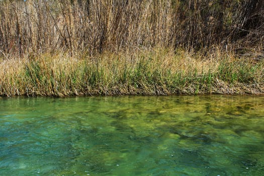 Cabriel River with crystal clear waters and surrounded by green vegetation in the mountains of Albacete, Spain