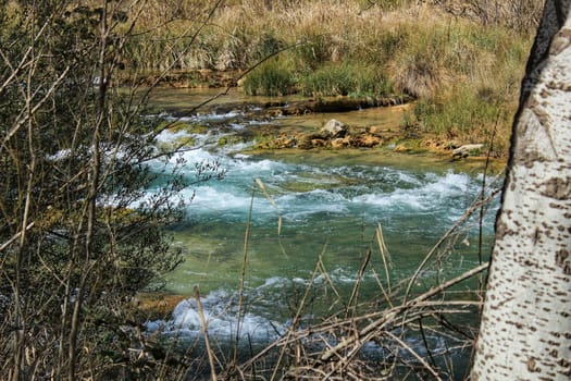 Cabriel River with crystal clear waters and surrounded by green vegetation in the mountains of Albacete, Spain