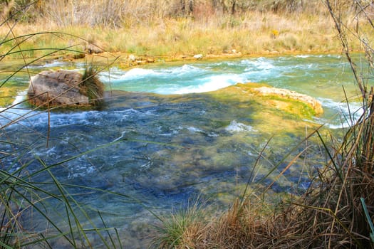 Cabriel River with crystal clear waters and surrounded by green vegetation in the mountains of Albacete, Spain