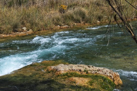 Cabriel River with crystal clear waters and surrounded by green vegetation in the mountains of Albacete, Spain