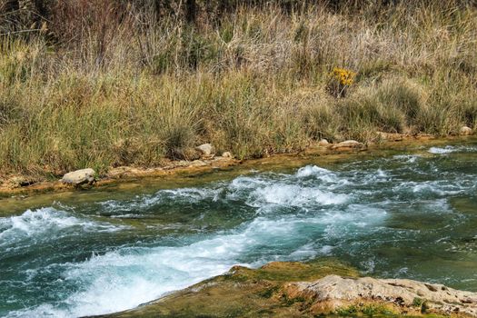 Cabriel River with crystal clear waters and surrounded by green vegetation in the mountains of Albacete, Spain