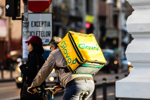 A Glovo food delivery courier on a bike. Restaurants are closed and only deliveries are allowed during the state of emergency due to coronavirus COVID-19 outbreak in Bucharest, Romania, 2020