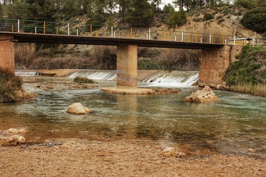 Cabriel River on its way through Casas del Rio village, Albacete, Spain. Landscape between cane field and mountains.