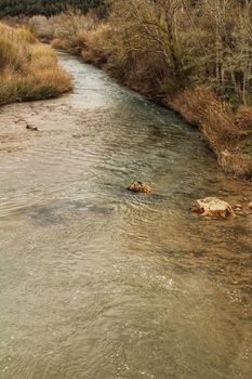 Cabriel River on its way through Casas del Rio village, Albacete, Spain. Landscape between cane field and mountains.