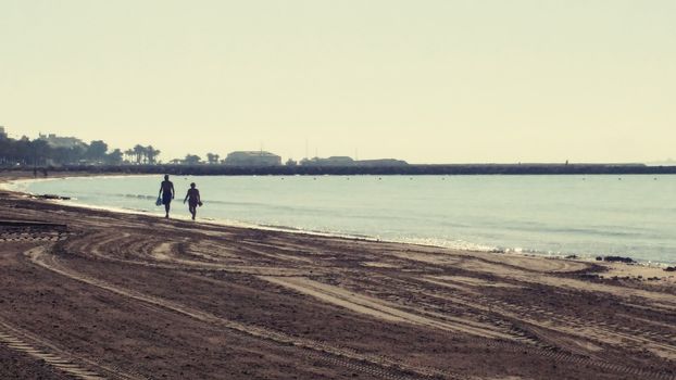 Couple walking by the seashore in a sunny day in Santa Pola, Alicante