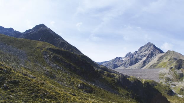 Aerial shot of the high mountains of the Austrian Alps in Kuhtai during summer season. The sunshine illuminates the beautiful landscape.