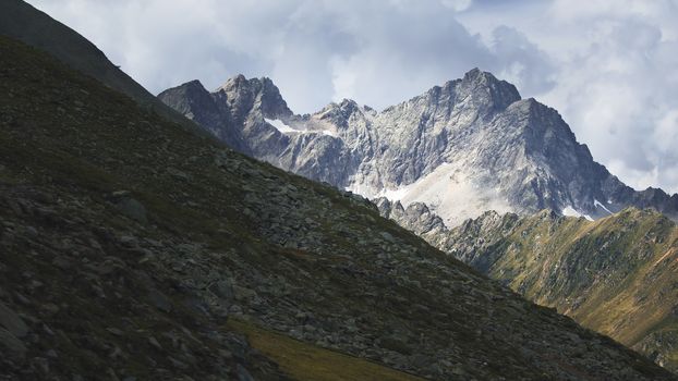 Aerial shot of the high mountains of the Austrian Alps in Kuhtai during summer season. The sunshine illuminates the beautiful landscape.