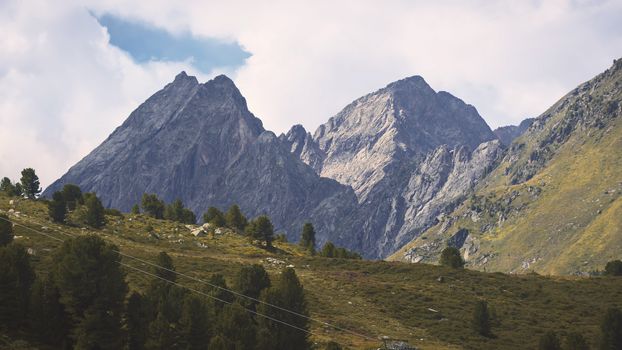 Aerial shot of the high mountains of the Austrian Alps in Kuhtai during summer season. The sunshine illuminates the beautiful landscape.