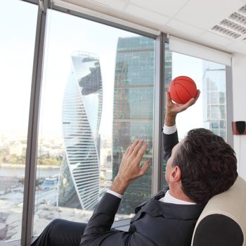 Business man playing with a basketball at the office