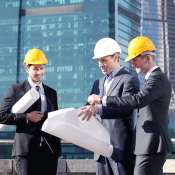 Architects with blueprint at skyscrapers background