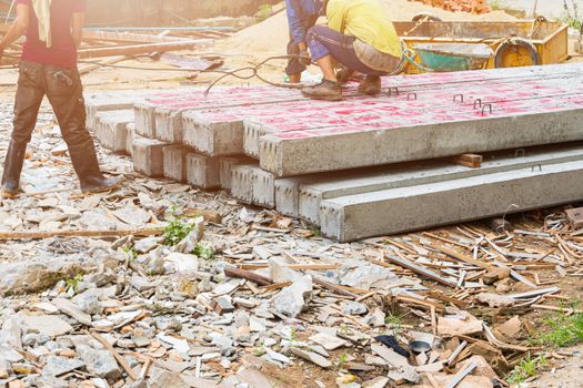 worker move pile concrete pillars on ground by sling in construction site