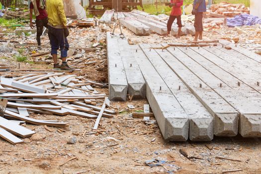 worker move pile concrete pillars on ground by sling in construction site