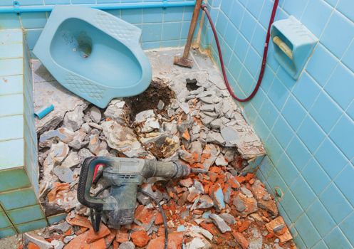 repair toilet old bathroom interior house and pneumatic hammer with Large steel hammer