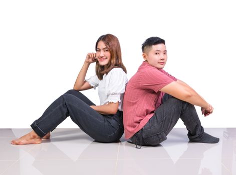 Two smiling woman young girls and happiness tomboy friends sitting back to back on tile floor in home with white background