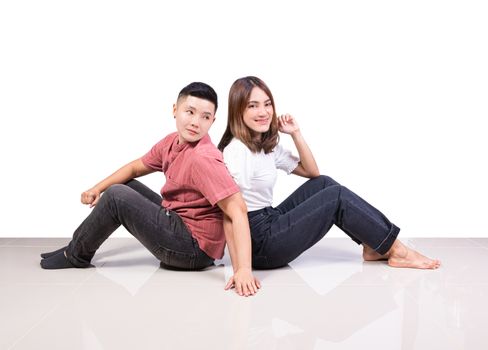 Two smiling woman young girls and happiness tomboy friends sitting back to back hold hand on tile floor in home with white background