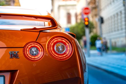 Rear lights of Orange Nissan Skyline GTR on a street waiting for green light