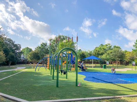 Residential neighborhood playground with sun shade sails and artificial grass in Flower Mound, Texas, America. Suburban recreational facility surrounded by wooden fence