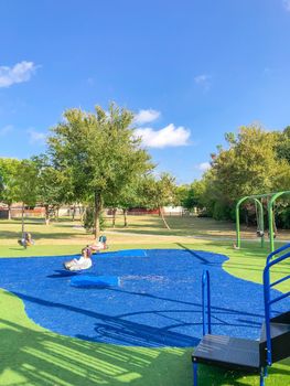 Neighborhood playground with artificial grass in Flower Mound, Texas, America. Suburban recreational facility surrounded by wooden fence