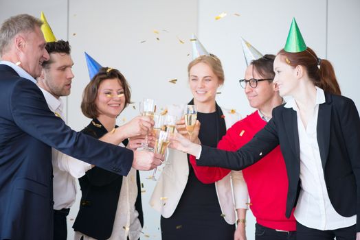 Happy business people holding flute with champagne and smiling at colleagues at party