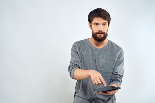 A man in a gray sweater a tablet in the hands of emotions Internet technology lifestyle light background. High quality photo