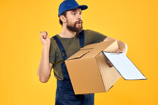 Worker male courier delivering boxes packaging documents yellow background. High quality photo