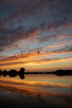 Reflection of colorful evening clouds in water after sunset, September view