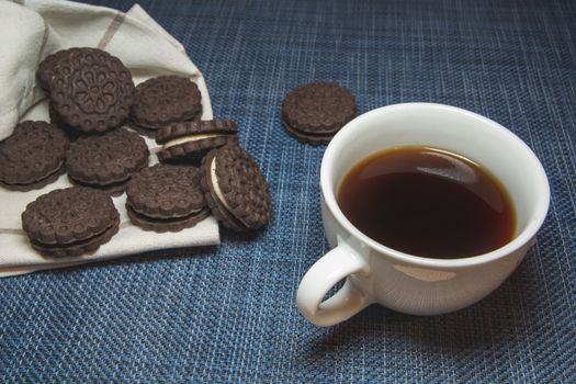 Coffee in a cup and brown cookies on a blue background