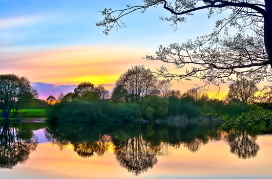 Beautiful sunset landscape at a lake with a reflective water surface.