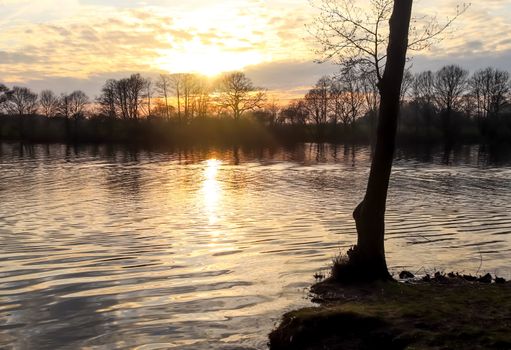 Beautiful sunset landscape at a lake with a reflective water surface.