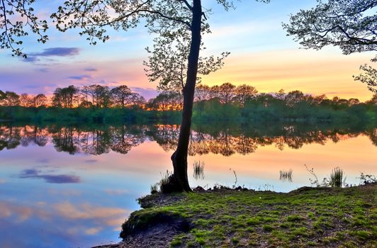 Beautiful sunset landscape at a lake with a reflective water surface.