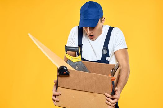 worker with box in hand tools loader yellow background. High quality photo