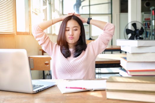 Young woman studying in a library and thinking of something